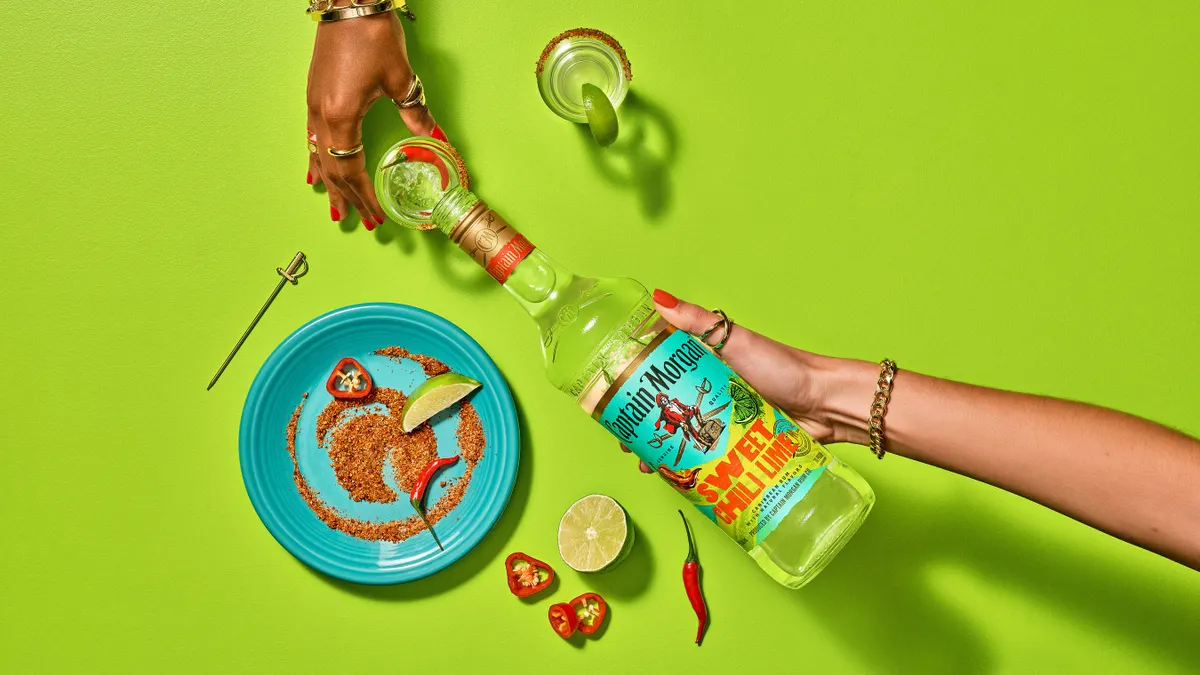 A bottle of Captain Morgan is poured over a lime-green backdrop from a bird's eye view