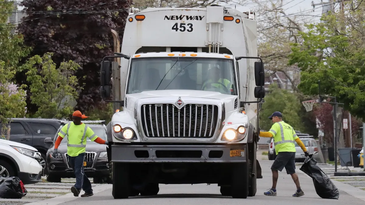 Workers collect waste on a street in Point Lookout, New York