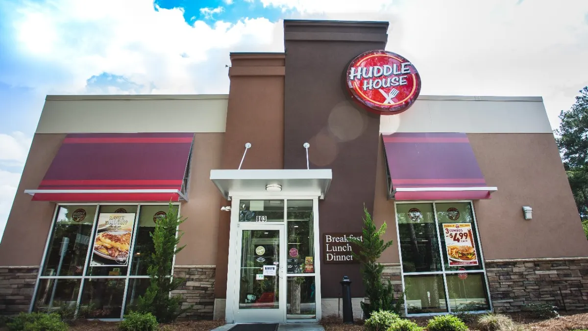 A photograph of a restaurant with the words Huddle House on the side.