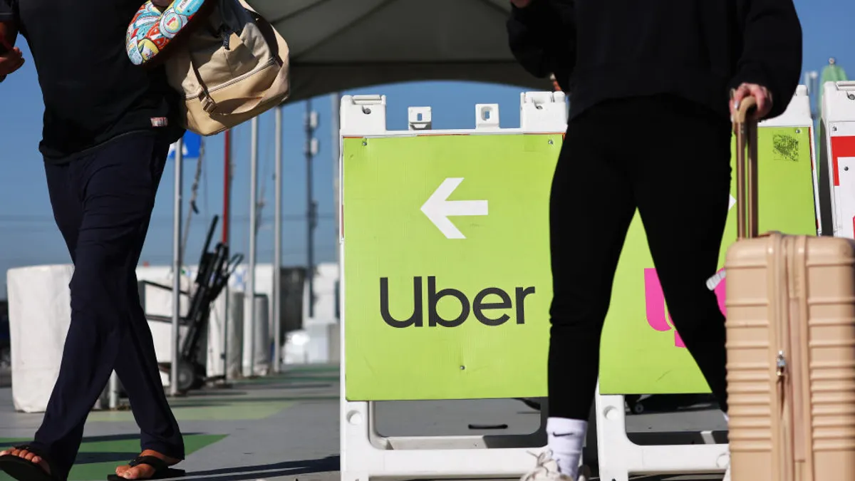 Travelers walk past a sign pointing toward the Uber rideshare vehicle pickup area at Los Angeles International Airport.
